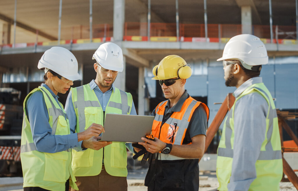 Diverse Team of Specialists Use Laptop Computer on Construction Site. Real Estate Building Project with Civil Engineer, Architectural Investor, Businesswoman and Worker Discussing Plan Details
